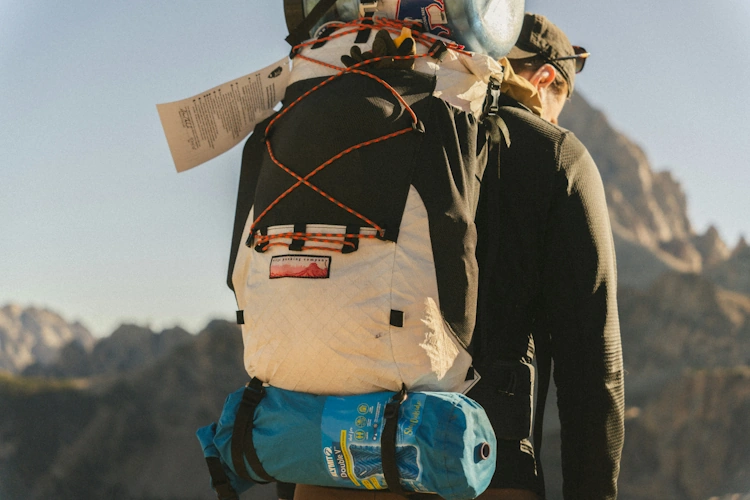 Hiker carrying large backpack traverses rugged mountain trail
